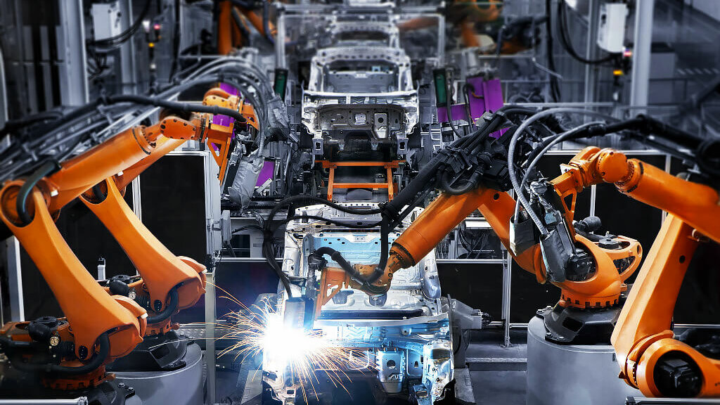 Robotic arms assembling vehicles in a modern factory.